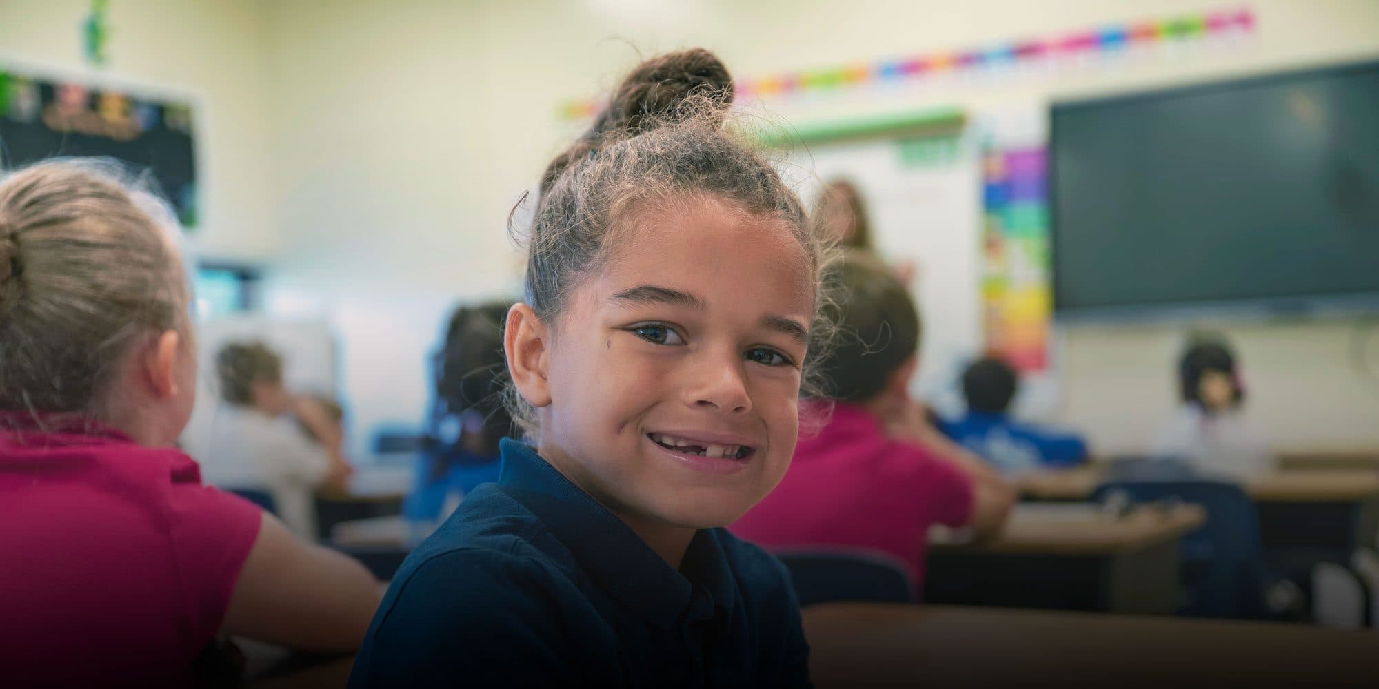 Smiling student at a desk in a Foundation Academy classroom.