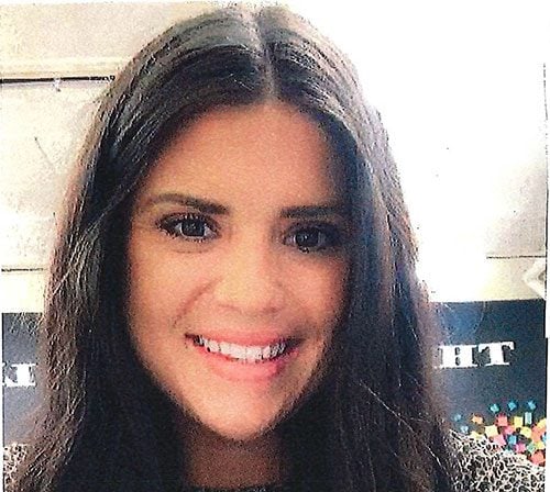 Smiling adult with long, dark hair looking at the camera.