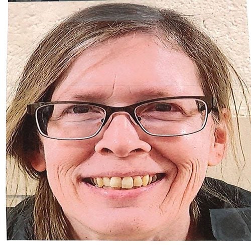 Smiling adult with light brown hair and glasses.