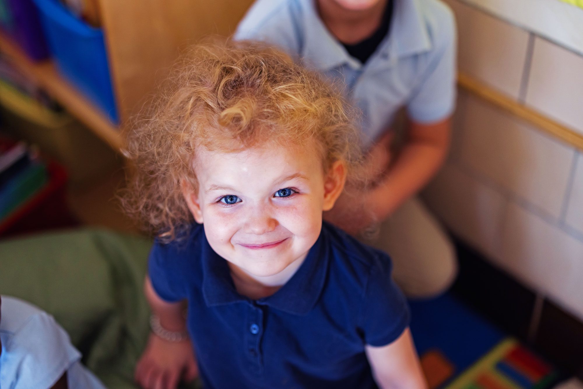 Smiling student with curly blonde hair wearing a blue polo shirt.