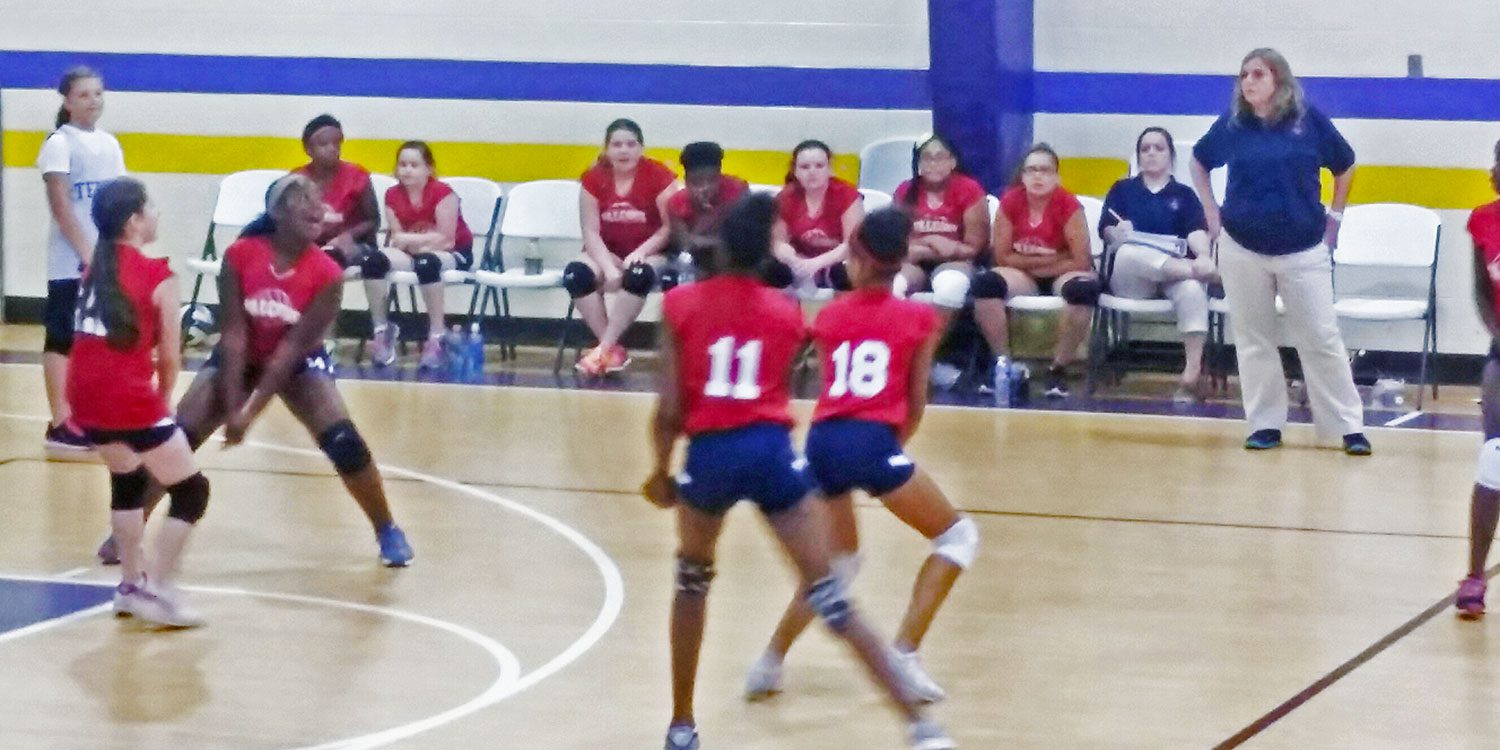 Students playing a volleyball game in the gym.